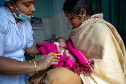 Head nurse, Priyanka Singh, assists a new mother, Bindiya Devi on how to handle her new born son before she feeds him, at Prabhawati Hospital, Gaya, Bihar.