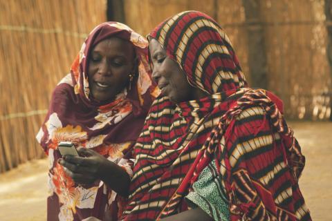 Women use a mobile phone, on Île de Fitiné, an island and fishing village in Lake Chad, Lac Region