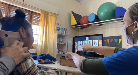 A caregiver helping a child navigate the platform on a digital tablet 